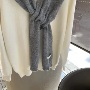 Écharpe en tricot gris et pull blanc vue de détail, accessoire d'hiver confortable.