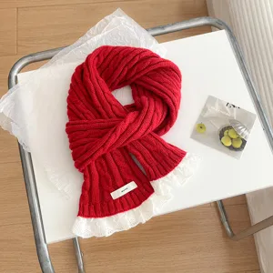 Close-up detail of the red knitted cable scarf featuring delicate white lace trim and cozy texture.