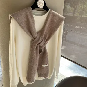 Gros plan détaillé du pull en tricot de laine doux associé à une écharpe élégante.