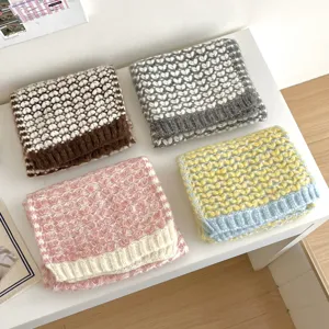 Vista detallada de cuatro bufandas de punto dobladas con diseño de corazones en colores cálidos.