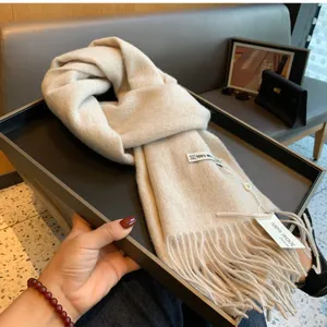 Detailaufnahme des beigen Wollschals mit weicher Strickstruktur und langen Fransen.