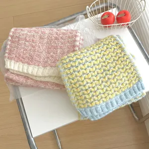 Vista detallada de bufandas de invierno de punto grueso con patrón de corazones rosa y amarillo.