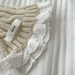 Knit cable scarf detail, beige wool texture with delicate white lace ruffle border.