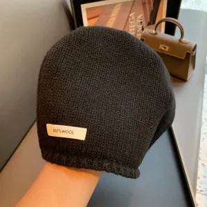 Detail view of a black 100% wool knit beanie hat, soft winter warm pullover cap texture.