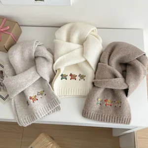 Detail view of soft warm knit scarf with cute colorful pony embroidery for autumn and winter.