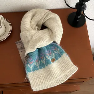 Detail view of a cozy warm knitted winter scarf with floral pattern on a retro wooden table.