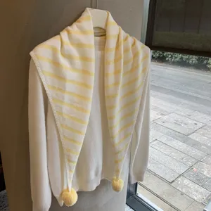 Knitted striped shawl scarf with pom poms, cozy winter warm triangular cape apparel detail.