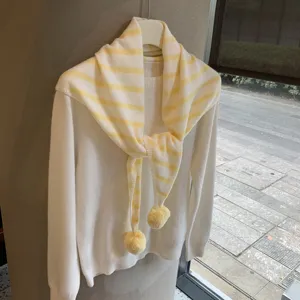 Detailed view of Japanese style striped knit scarf with cute pom-poms, soft and warm accessory.