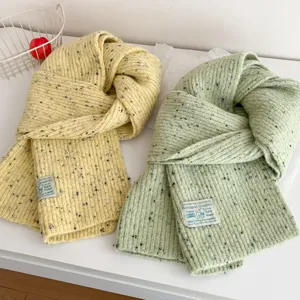 Close-up of winter speckled knit scarves in yellow and mint green, featuring cozy texture.