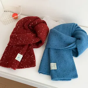 Close up detail of soft colorful speckle knit winter scarfs in red and blue with small tags.