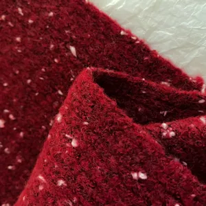 Close-up detail of soft red knitted winter scarf fabric featuring cozy colorful nep texture.