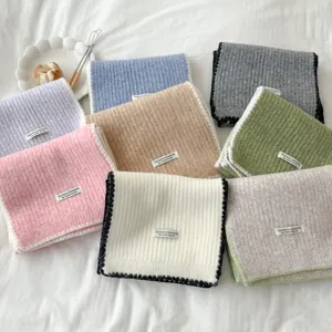 Detailed view of cozy knit winter scarves in multiple solid colors with contrast stitching.