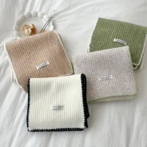Detailed view of cozy knit winter scarves with contrast edge design and handmade style label.