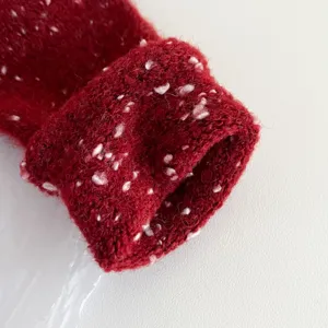 Close-up view of soft red knitted winter scarf texture featuring cute white speckle details.