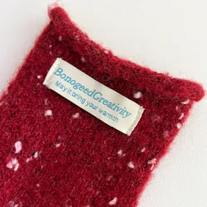 Close-up detail of red colorful dot knitted winter scarf fabric texture and branded label.
