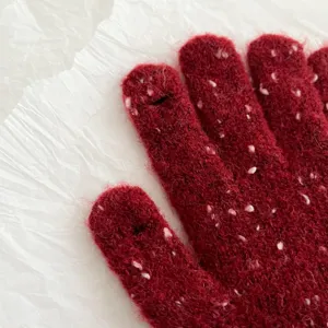 Close-up detail of cozy winter red knitted gloves featuring soft white speckles texture.
