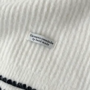 Close-up detail of white knitted winter scarf fabric texture with woven brand label.