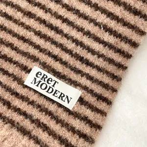 Brown striped knit scarf detail showing soft woolen texture and woven brand label.