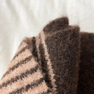 Close-up detail of cozy brown striped knitted scarf, soft fuzzy texture for winter warmth.