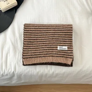 Brown striped knit scarf detail showing soft textured wool fabric and modern label branding.