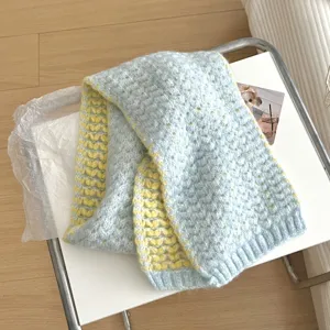 Detalle en primer plano de una bufanda de punto suave con corazones azules y amarillos.