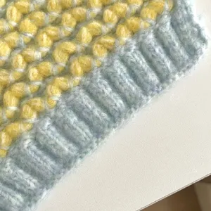 Primer plano del detalle de la bufanda de punto, suave patrón texturizado amarillo y azul.