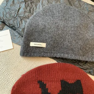 Grey wool knit beanie hat detail view, winter warm slouchy cap with wool label and cute cat.