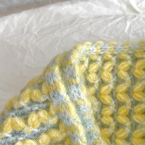 Primer plano detallado de la textura suave de la bufanda tejida en hilo amarillo.