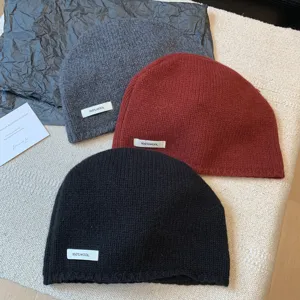 Detailed shot of 100% pure wool knitted beanie hats in grey, red, and black colors.