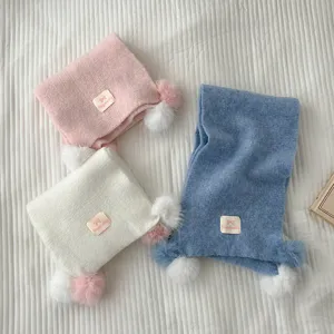 Cozy knit winter scarf with cute plush pom poms, soft warm material, stylish multi-color fashion accessory.