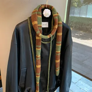 Close-up of retro brown and green striped knitted narrow scarf styled on a black leather jacket.
