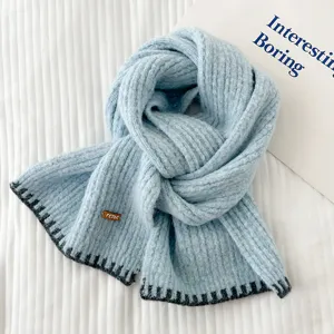 Suave bufanda de punto azul claro con borde oscuro contrastante y etiqueta elegante.