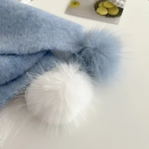 Close-up detail shot of cozy winter fuzzy knitted scarf featuring cute dual pom-poms.