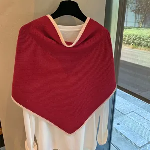 Primer plano detallado del pañuelo triangular de punto rojo con ribete de contraste.