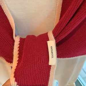 Primer plano de la bufanda de punto rojo con bordes rosados, mostrando textura suave