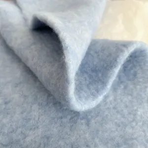 Close-up detail of soft light blue fuzzy winter scarf fabric, showing cozy plush texture.