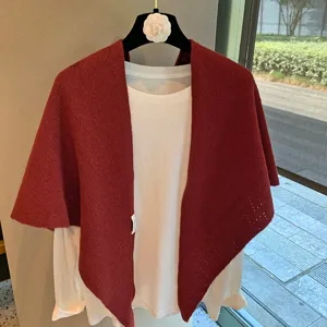 Detailed close-up of a solid red knitted triangular scarf shawl layered over a white top.