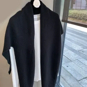 Detailed view of the black knit wool shawl draped over a white shirt, soft texture and warm style.
