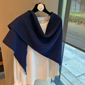 Detailed view of the dark blue knitted triangle scarf shawl paired with a white long-sleeve tee.
