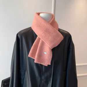 Primer plano de los detalles de la bufanda de punto rosa suave con textura y etiqueta metal.