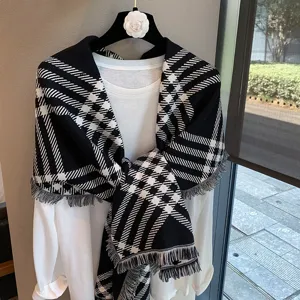 Close-up of black and white houndstooth knit scarf with fringe, elegant winter shawl detail.