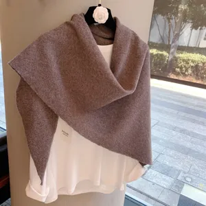 Brown knitted triangular shawl detail shot, soft wool texture, elegant autumn winter fashion accessory.