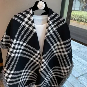 Black and white plaid knit shawl cape, winter warm scarf, classic pattern cozy clothing detail.