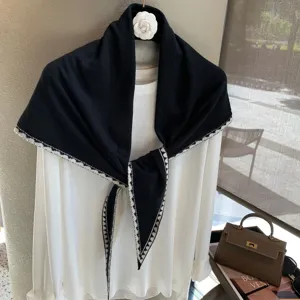 Detalle de bufanda triangular de punto, borde jacquard blanco y negro, chal elegante.