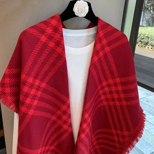 Red plaid winter shawl for women, cozy fringed tartan cape, stylish elegant outerwear.