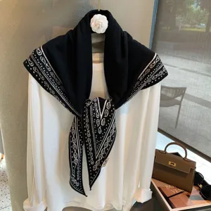Vista detallada de bufanda triangular de punto jacquard en blanco y negro como chal versátil.