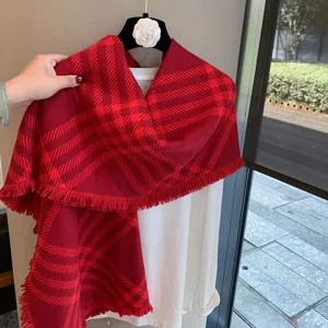 Red plaid winter scarf detail, soft warm shawl with fringe, cozy fashion accessory.