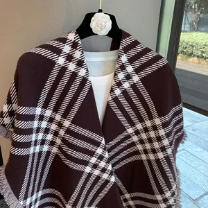 Detail view of the elegant brown and white plaid knitted shawl with chic fringe border design.