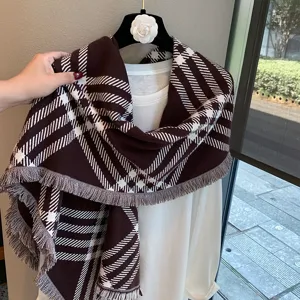 Detailed close-up of brown and white plaid knitted scarf with elegant fringe trim and cozy drape.