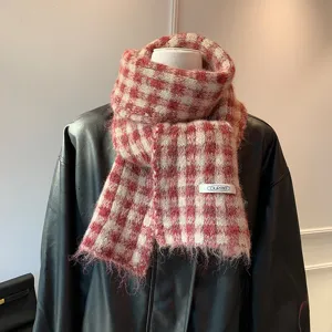 Close-up detail of cozy red and white plaid knit winter scarf with fringe and brand label.